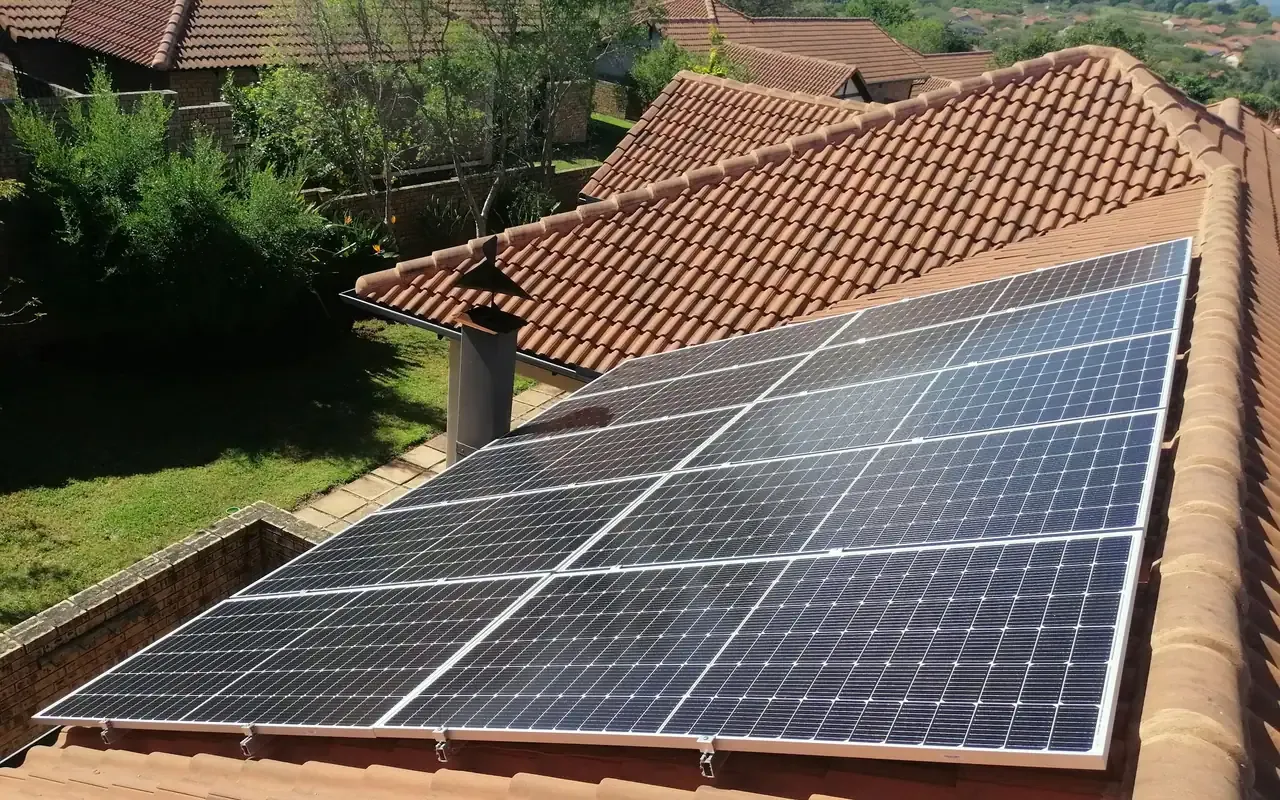 Solar panels on a red clay-tile roof surrounded by trees
